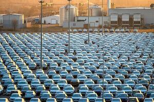 Volkswagen Group Rus, Russia, Kaluga - NOVEMBER 17, 2020 Rows of a new cars parked in a distribution center on a sunny autumn morning and a car factory buildings. photo