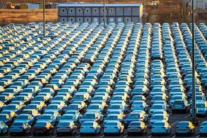 Volkswagen Group Rus, Russia, Kaluga - NOVEMBER 17, 2020 Rows of a new cars parked in a distribution center on a sunny autumn morning and a car factory buildings. photo