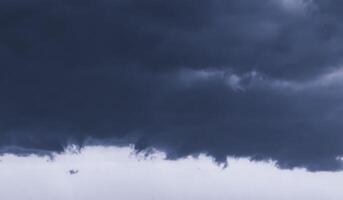 Dark monochrome heavy storm clouds before a thunderstorm or hurricane. Dramatic clouds in overcast weather. photo