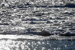 Melting ice floating on the river on a spring day. Cracked ice texture. photo