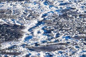 Melting ice floating on the river on a spring day. Cracked ice texture. photo