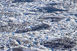Melting ice floating on the river on a spring day. Cracked ice texture. photo