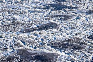 Melting ice floating on the river on a spring day. Cracked ice texture. photo