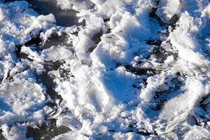 Melting ice floating on the river on a spring day. Cracked ice texture. photo