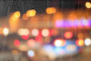 Night city lights and car headlights through rainy glass. Rain and bad weather concept. photo
