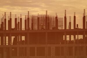Silhouette of a team of construction workers constructing a building against the background of a sunset sky. photo