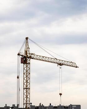 A team of construction workers in and a crane constructing a building on the background of the evening cloudy sky. photo