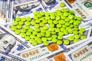 Green pills on the background of one hundred dollar bills. photo