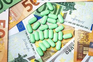 Green pills on the background of one hundred dollar bills. photo