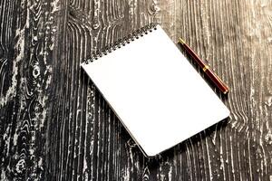 The notebook with squared pages and pen on a black table with a copy space. photo