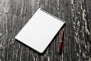 The notebook with squared pages and pen on a black table with a copy space. photo