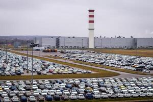 New cars parked in a distribution center on a cloudy rainy day in the autumn, a car factory. photo