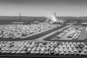 New cars parked in a distribution center on a cloudy rainy day in the autumn, a car factory. photo