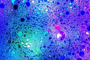 Colorful drops of oil on the water. Blue and violet colored circles and ovals. Abstract background for design. photo