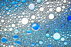 Top view on colorful drops of oil on the water. Blue circles and ovals. Abstract bright background for design. photo