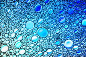 Top view on colorful drops of oil on the water. Blue circles and ovals. Abstract bright background for design. photo