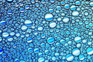 Top view on colorful drops of oil on the water. Blue circles and ovals. Abstract bright background for design. photo
