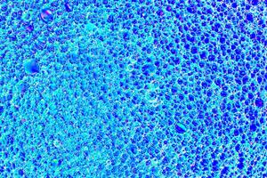 Top view on colorful drops of oil on the water. Blue circles and ovals. Abstract bright background for design. photo