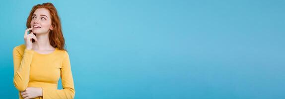Portrait of happy ginger red hair girl with freckles smiling looking at camera. Pastel blue background. Copy Space photo