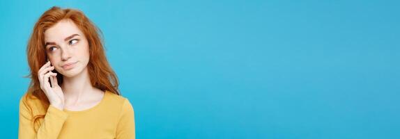 Lifestyle and Technology concept - Portrait of ginger red hair girl with shocking and stressful expression while talking with friend by mobile phone. Isolated on Blue Pastel Background. Copy space. photo