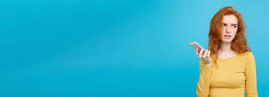Lifestyle and Technology concept - Portrait of cheerful happy ginger red hair girl with joyful and exciting smiling to camera. Isolated on Blue Pastel Background. Copy space. photo