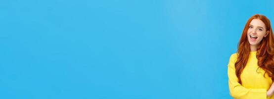 Waist-up shot carefree cheerful and friendly redhead gorgeous female freelancer finished IT school and showing okay gesture, no problem sign, smiling unbothered, assure all good, blue background photo