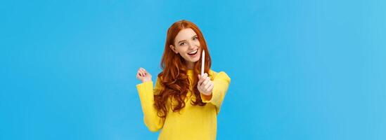 Be author of your own future. Cheerful and creative excited redhead woman giving you pen and smiling, want autograph, want friend draw something, smiling joyfully, standing blue background photo