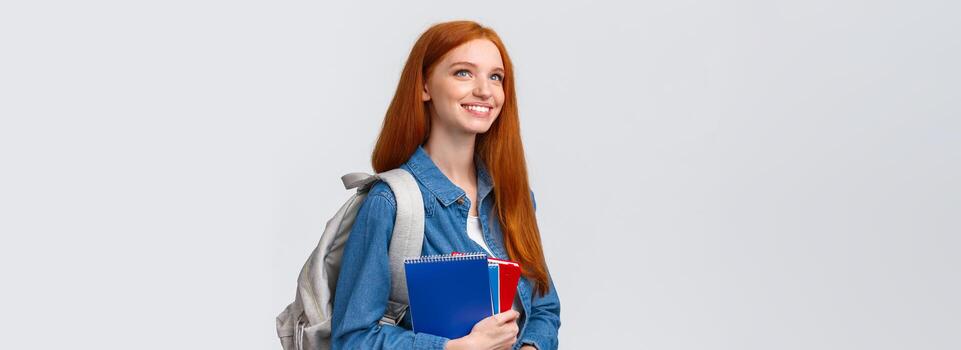 juventud, adolescentes y educación concepto. determinado guapo soñador y optimista sonriente pelirrojo hembra estudiante con cuadernos y mochila mirando adelante nuevo tema en clase foto