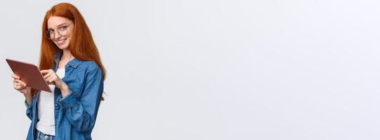 Wait-up portrait coquettish and flirty cute redhead woman flirting with team member during meeting, holding digital tablet, looking seductive camera with alluring smile, white background photo