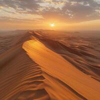 Sun casting warm glow on sandy dune in desert as it sets photo