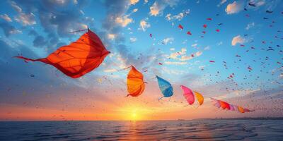 At sunset, a collection of kites soar through the sky above the ocean photo