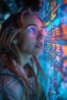 A woman wearing glasses is sitting in front of a computer monitor photo