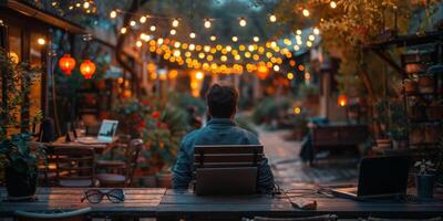 A man is seated at a table with a laptop placed on it photo