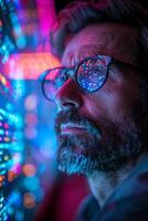 A man with glasses and a beard looks at a computer screen photo