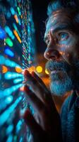 Man with a beard using computer in dark room, looking at event graphics photo