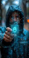 A man wearing a hoodie is seen holding a digital padlock in his hand photo