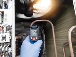Checking and measuring temperature using a thermo gun in the refrigeration system in HVAC air conditioning. Refrigeration check using thermo gun with concept professional hvac service. photo