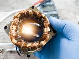 fan winding repair by a technician using blue gloves, fan motor winding repair concept. photo