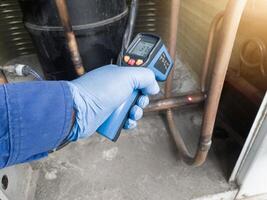 Checking and measuring temperature using a thermo gun in the refrigeration system in HVAC air conditioning. Refrigeration check using thermo gun with concept professional hvac service. photo