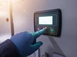 The electrician engineer wear the blue gloves, check and control interlock generator system on the panel power plant.Check and maintenance auto control generator switch gear. photo