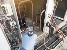 Professional engineer wearing blue gloves using thermo gun for temperature check on the hvac air cinditioning syatem. Temperature check concept on the compressor, condensor , refrigerant system hvac. photo