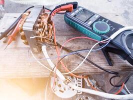 Fan motor winding repair process, concept of checking and repairing motor windings using a tester. photo