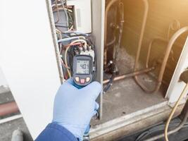 Professional engineer wearing blue gloves using thermo gun for temperature check on the hvac air cinditioning syatem. Temperature check concept on the compressor, condensor , refrigerant system hvac. photo