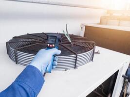 Measuring and checking the temperature of the condenser ventilation using a temperature gun by an engineer photo