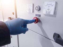 A hand engineer push the Emergency Push Botton on panel control when emergency condition.How to use emergency switch on panel control power plant. photo