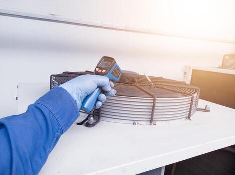Measuring and checking the temperature of the condenser ventilation using a temperature gun by an engineer photo