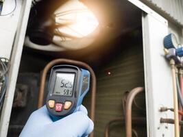 Checking and measuring temperature using a thermo gun in the refrigeration system in HVAC air conditioning. Refrigeration check using thermo gun with concept professional hvac service. photo