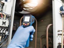 Checking and measuring temperature using a thermo gun in the refrigeration system in HVAC air conditioning. Refrigeration check using thermo gun with concept professional hvac service. photo