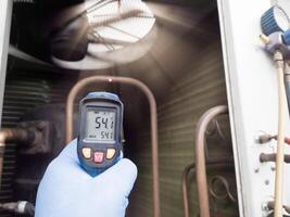 Checking and measuring temperature using a thermo gun in the refrigeration system in HVAC air conditioning. Refrigeration check using thermo gun with concept professional hvac service. photo