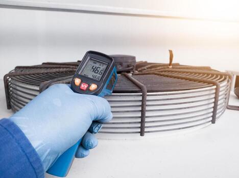 Measuring and checking the temperature of the condenser ventilation using a temperature gun by an engineer photo
